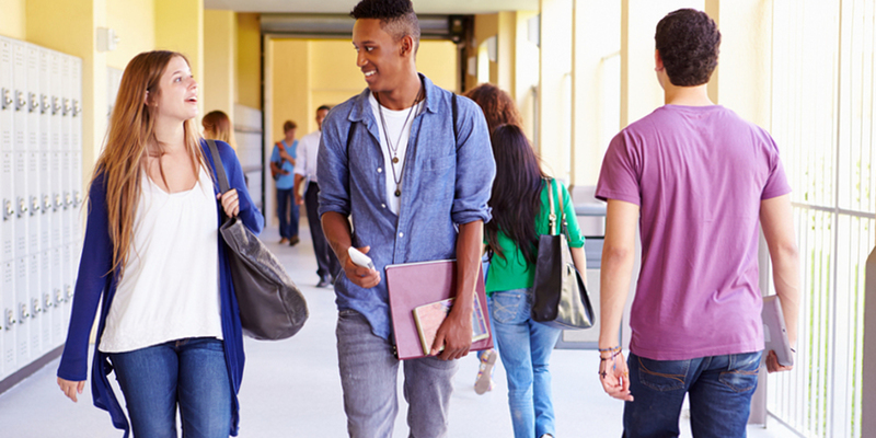 Medium high school students walking down hallway talking feature image